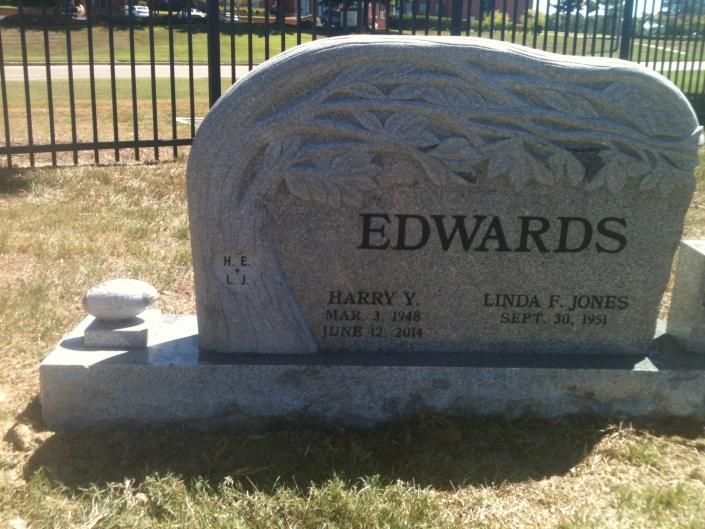 Gravestone with the name EDWARDS in a cemetery, featuring two small flower pots on the base.
