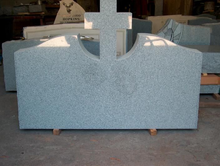 Gray granite tombstone with a cross-shaped top in a cemetery workshop