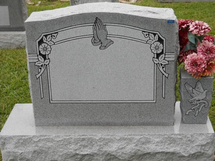 Gray gravestone with butterfly engraving and pink flowers beside it in a cemetery