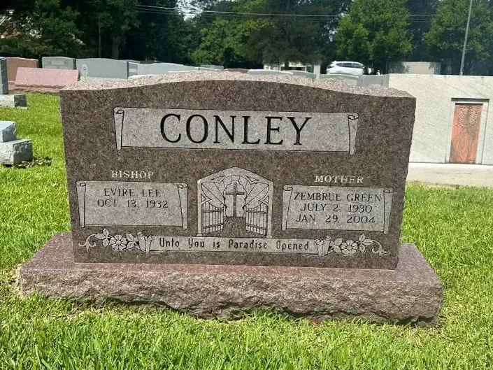 Conley family gravestone with engraved names and house illustration in a cemetery