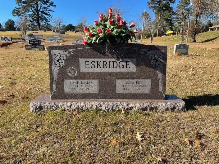ESKRIDGE family gravestone with pink and white flowers in a sunny cemetery