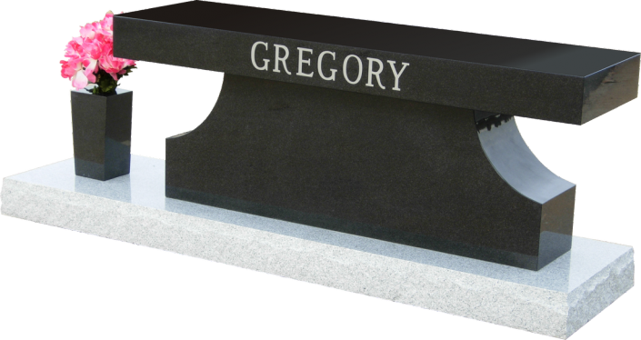 Black granite memorial bench with “GREGORY” engraved and pink flowers in a vase on the left