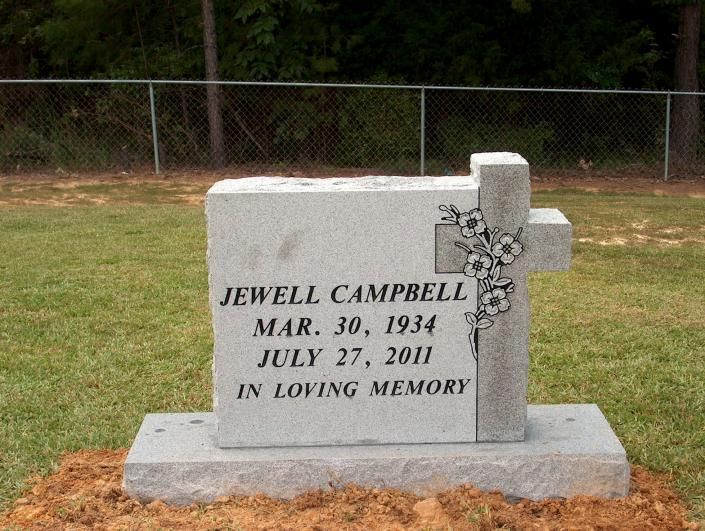 Gravestone for Jewell Campbell with floral engraving in a cemetery setting.
