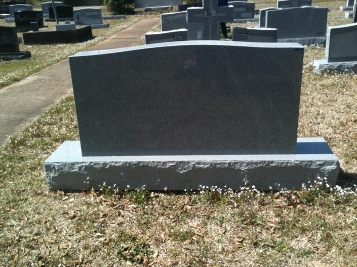 Black granite gravestone in a cemetery with grass and other headstones in the background
