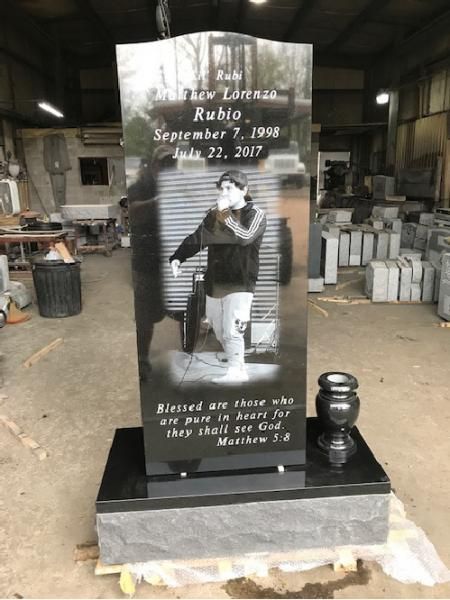 Decorative black memorial monument with a child photo, text inscriptions, and a vase in an indoor workshop