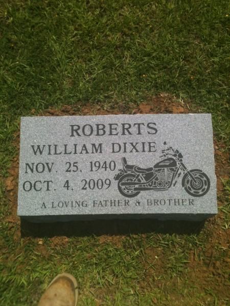 Gravestone for William Dixie Roberts with motorcycle engraving, set in grass.