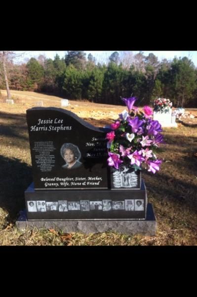 Black gravestone with engraved photo and purple flowers in a cemetery