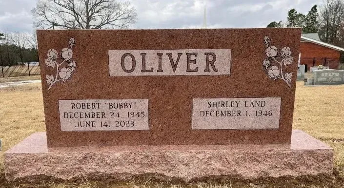 Granite memorial bench with “OLIVER” plaque and carved names in a cemetery setting