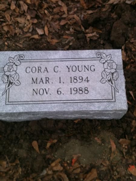 Gray gravestone engraved “Cora C. Young, Mar. 1, 1894, Nov. 6, 1988” on fallen leaves