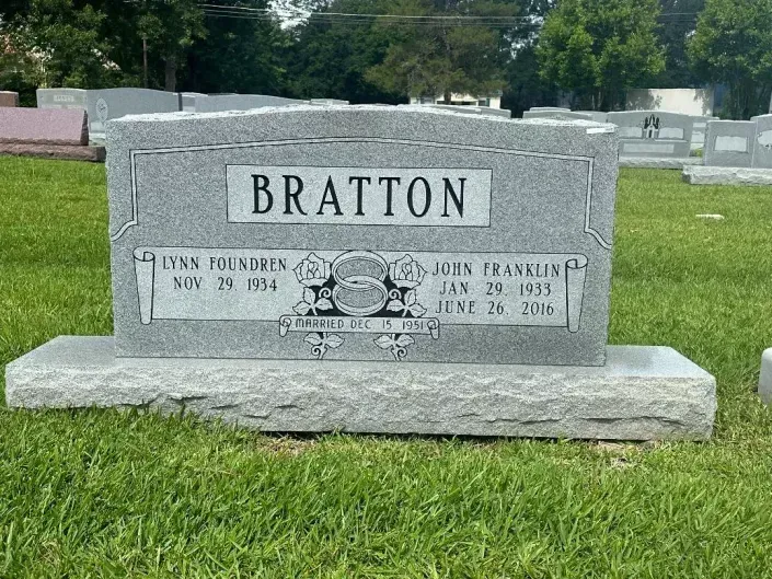 Gravestone with BRATTON engraved, sitting in a grassy cemetery.