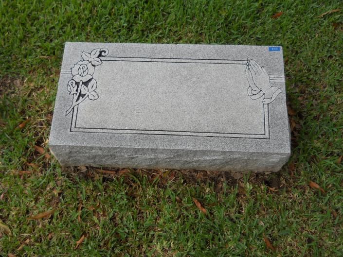 Gray engraved gravestone with floral corners on grass