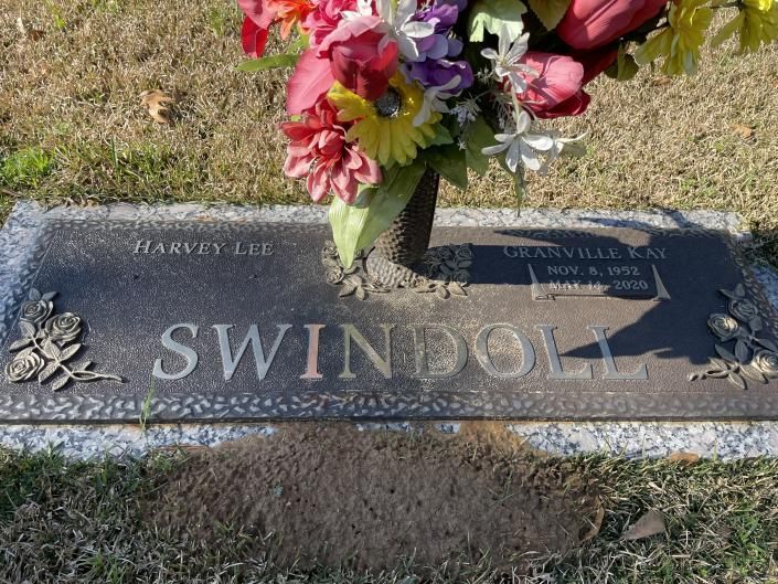 Floral bouquet on a gravestone engraved “SWINS…” in a cemetery