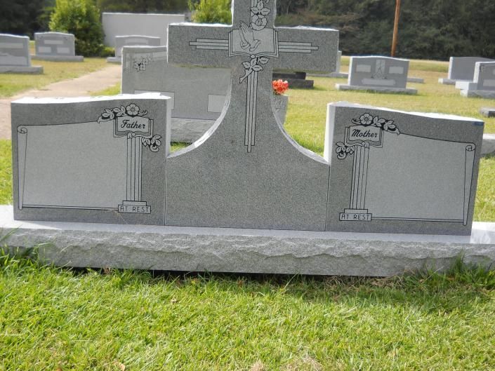 Gray granite cemetery headstone with curved center and two engraved side panels on grass.
