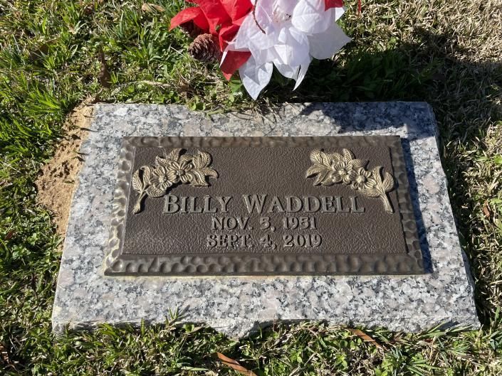 Gravestone for Billy Wadell with flowers placed above it on grass