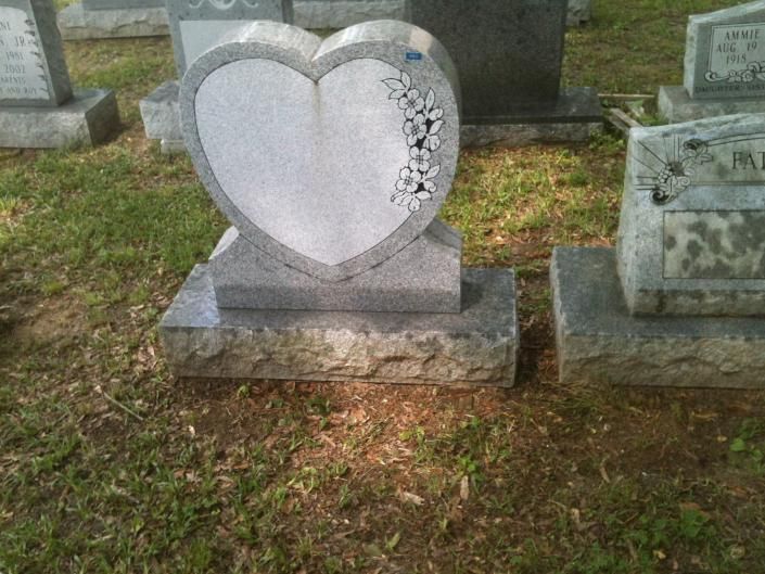 Heart-shaped gravestone in a cemetery, with a cracked floral design on the right side.