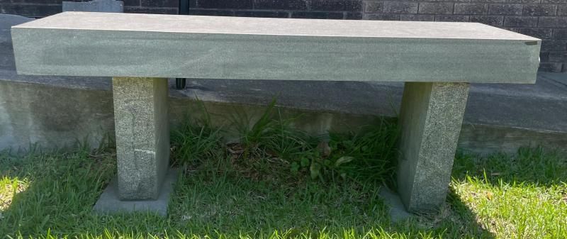 Concrete bench in a grassy outdoor area with two support legs