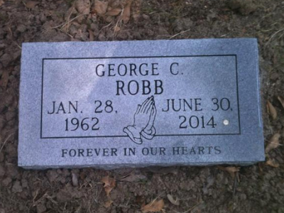 Gray gravestone engraved “George C. Robb,” dates Jan. 28, 1962–June 30, 2014, with praying hands icon.