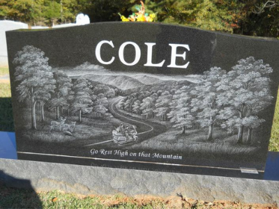 Black granite memorial with “COLE” and a carved mountain landscape scene.