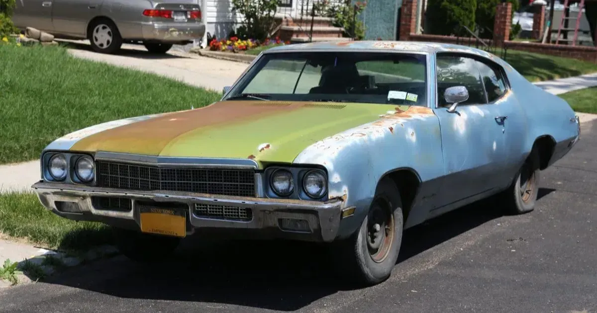 Light green vintage coupe parked on a residential street in daylight
