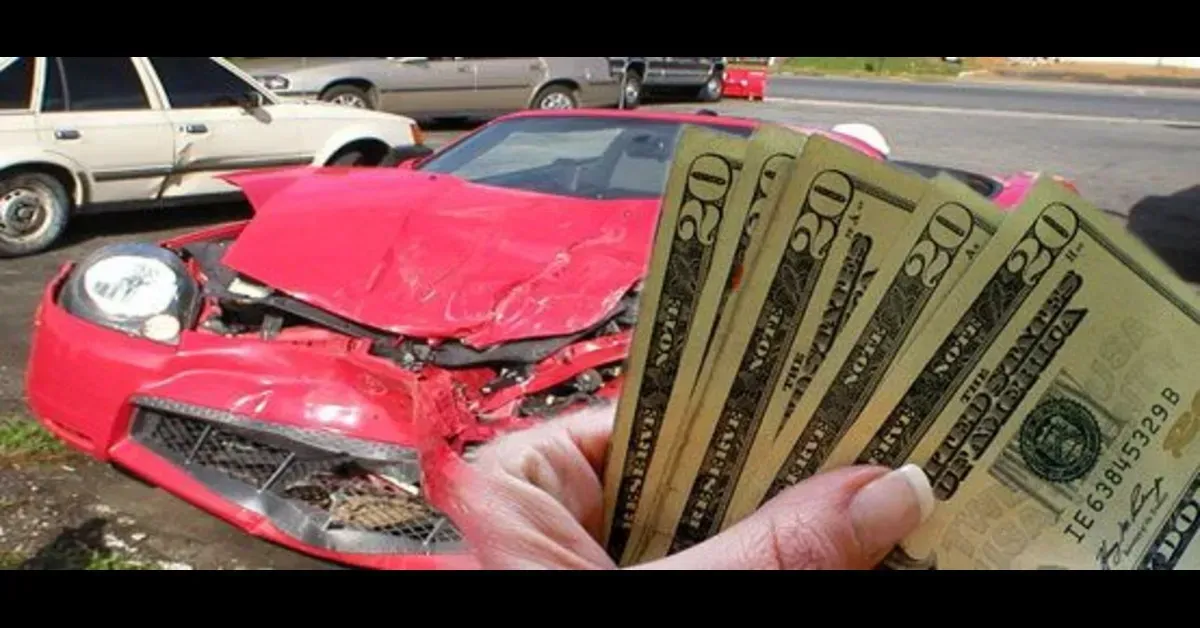 Hand holding cash in front of a wrecked red car at a traffic accident scene