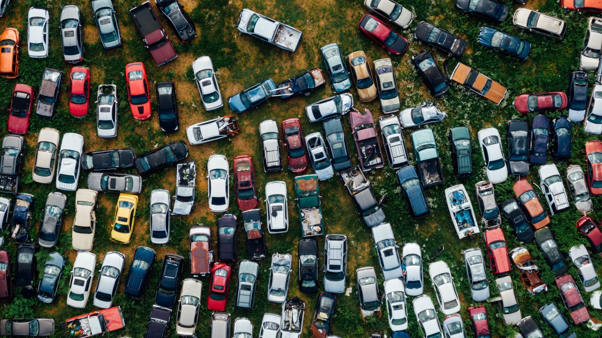Aerial view of many parked cars densely packed on a grassy lot