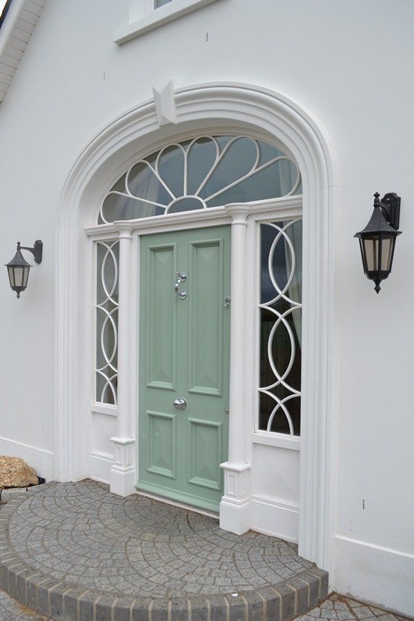 The front door of a white house with a green door