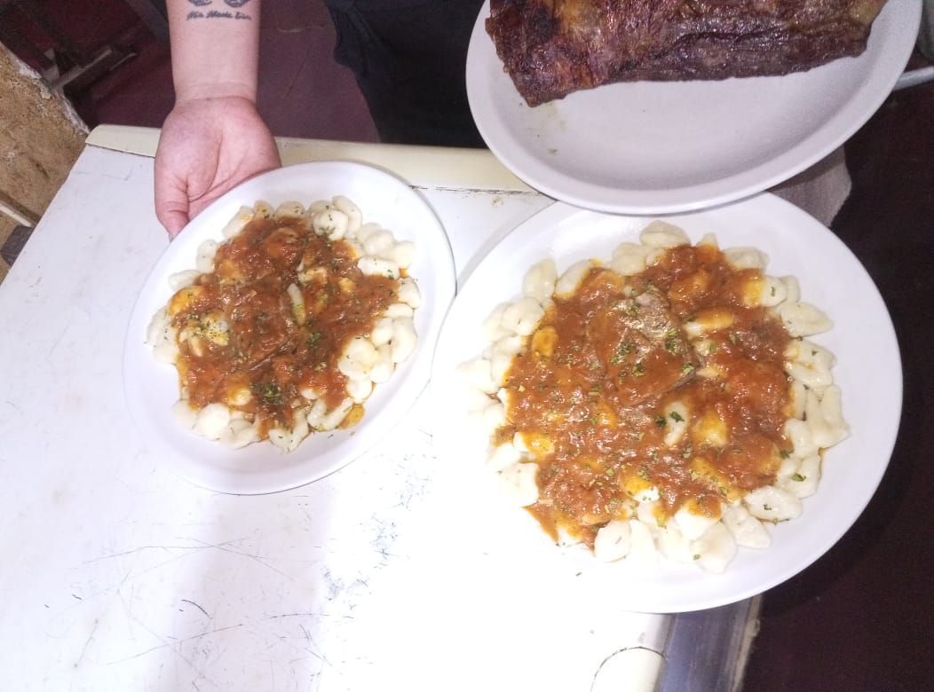 Platos de pasta con salsa, sostenidos por una persona. En un tercer plato, un filete.