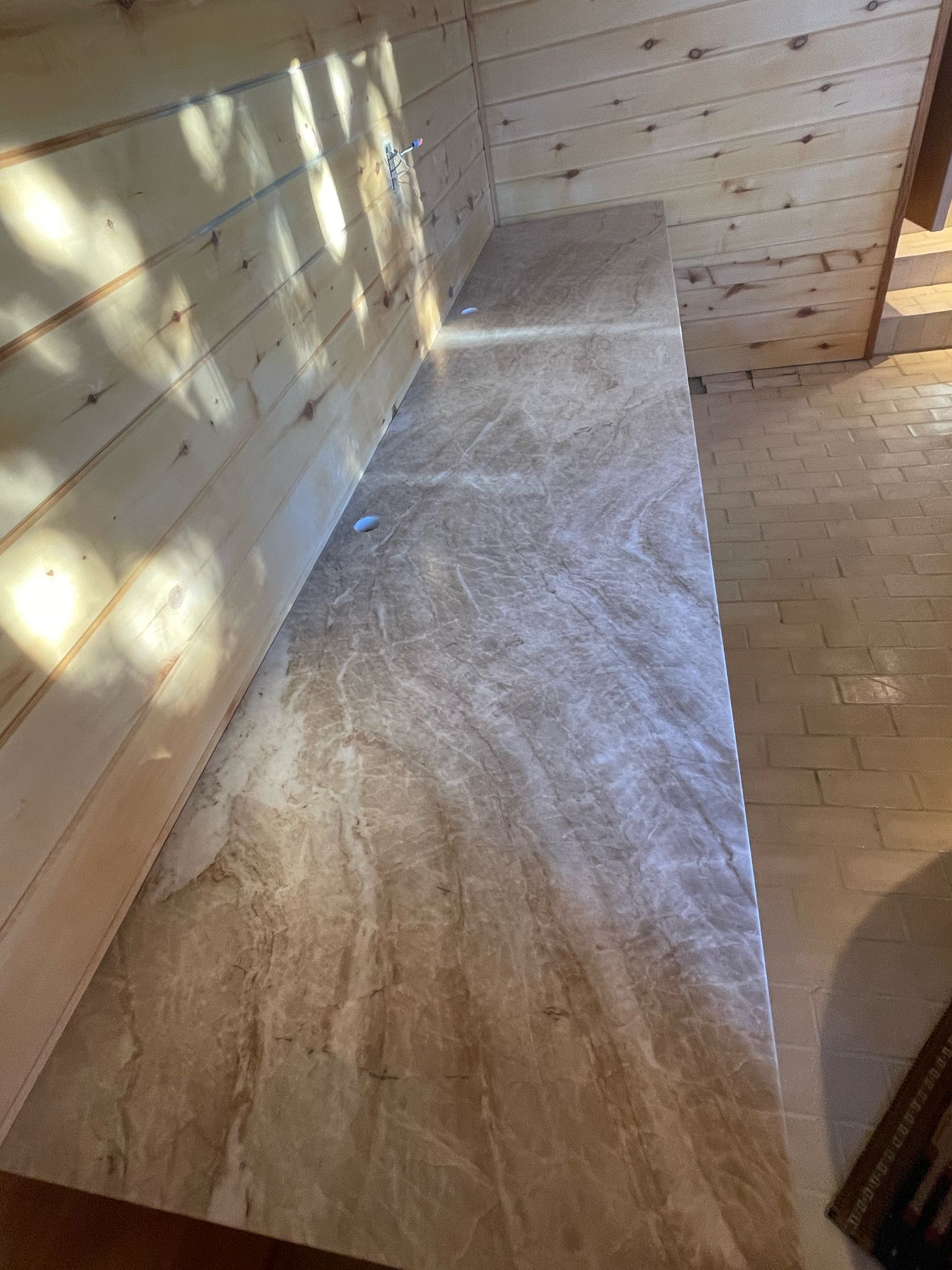 A long, beige countertop against a light wood wall and ceiling.