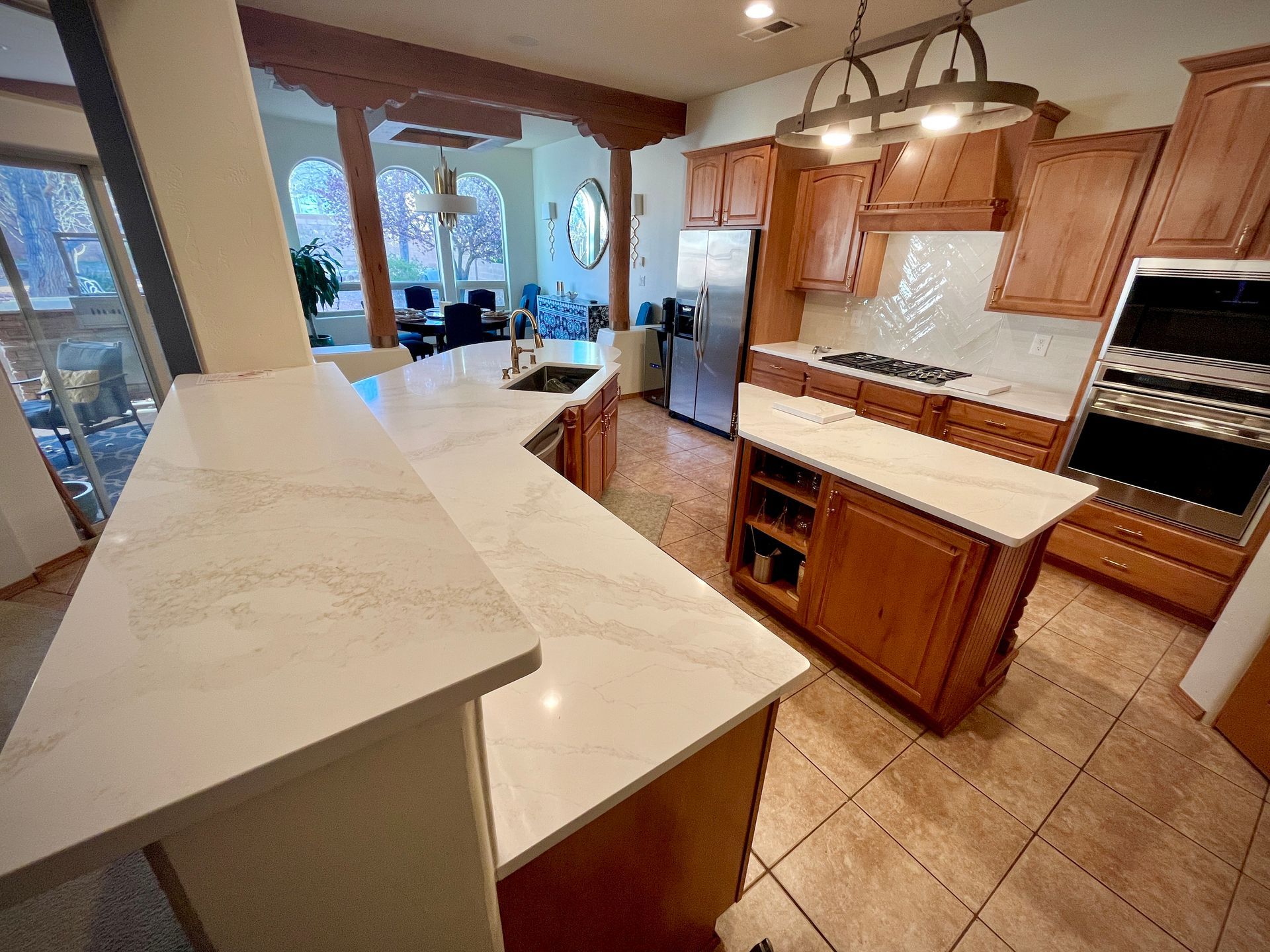A modern kitchen with wood cabinets, white countertops, and a center island.