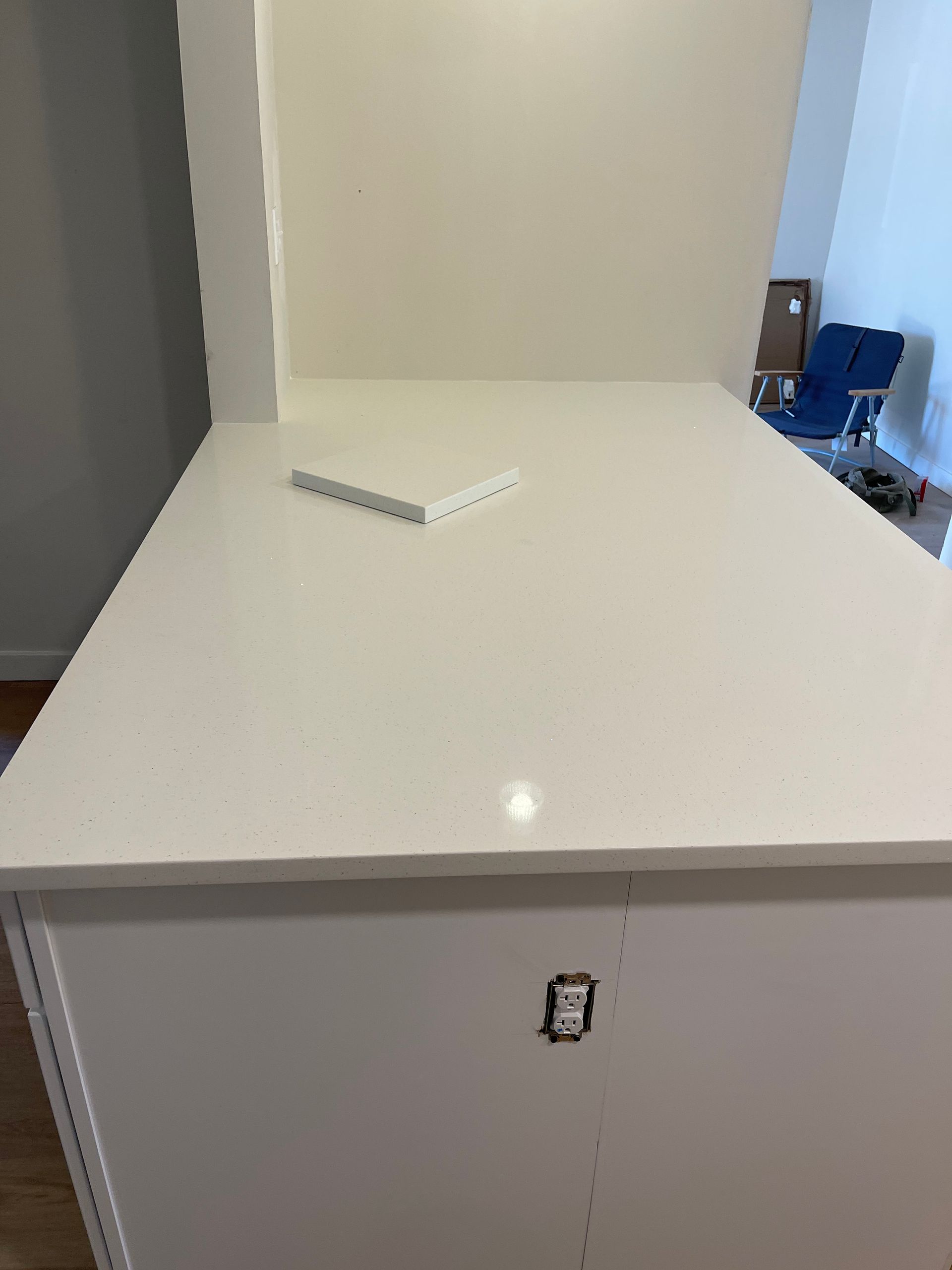 White countertop in a room with a small remote resting on it and a cabinet below.