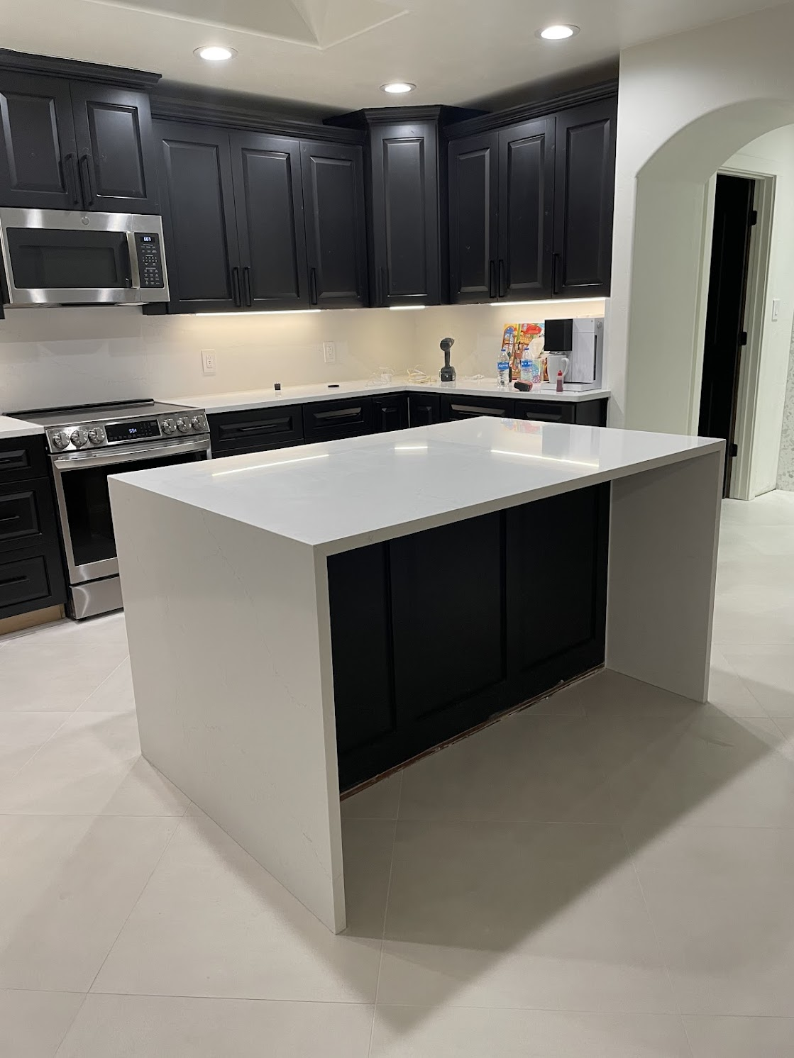 Modern kitchen with black cabinets, white countertops, and an island.