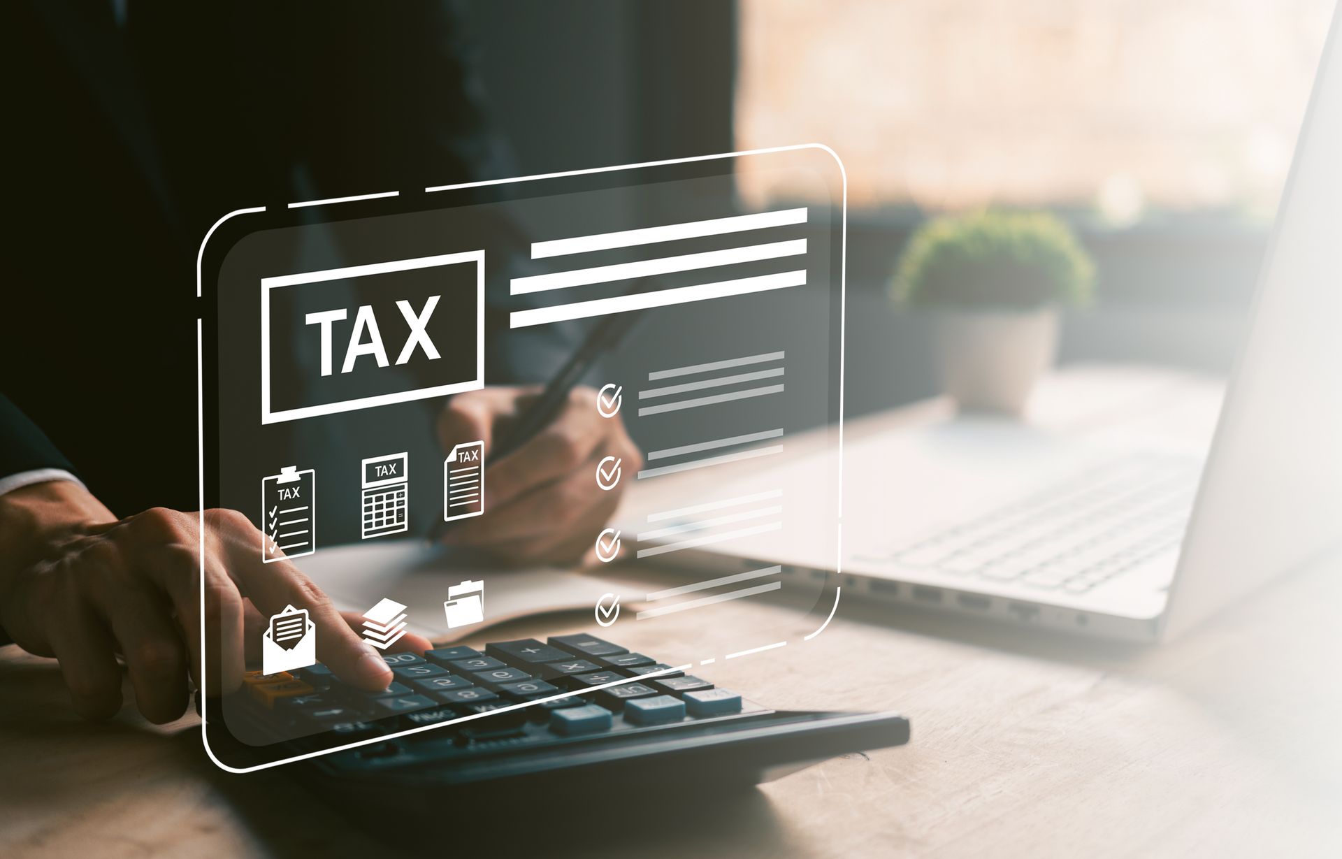 Tax preparation interface over a calculator beside a laptop.