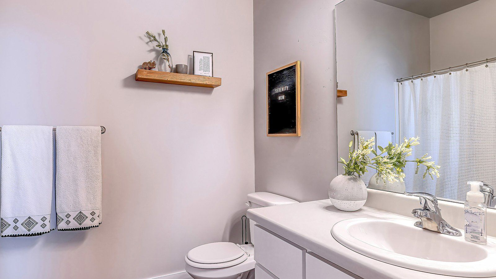 Bathroom Remodeling Services in Albany County, WY Bright bathroom with white vanity, sink, towels, mirror, and a small shelf with plants