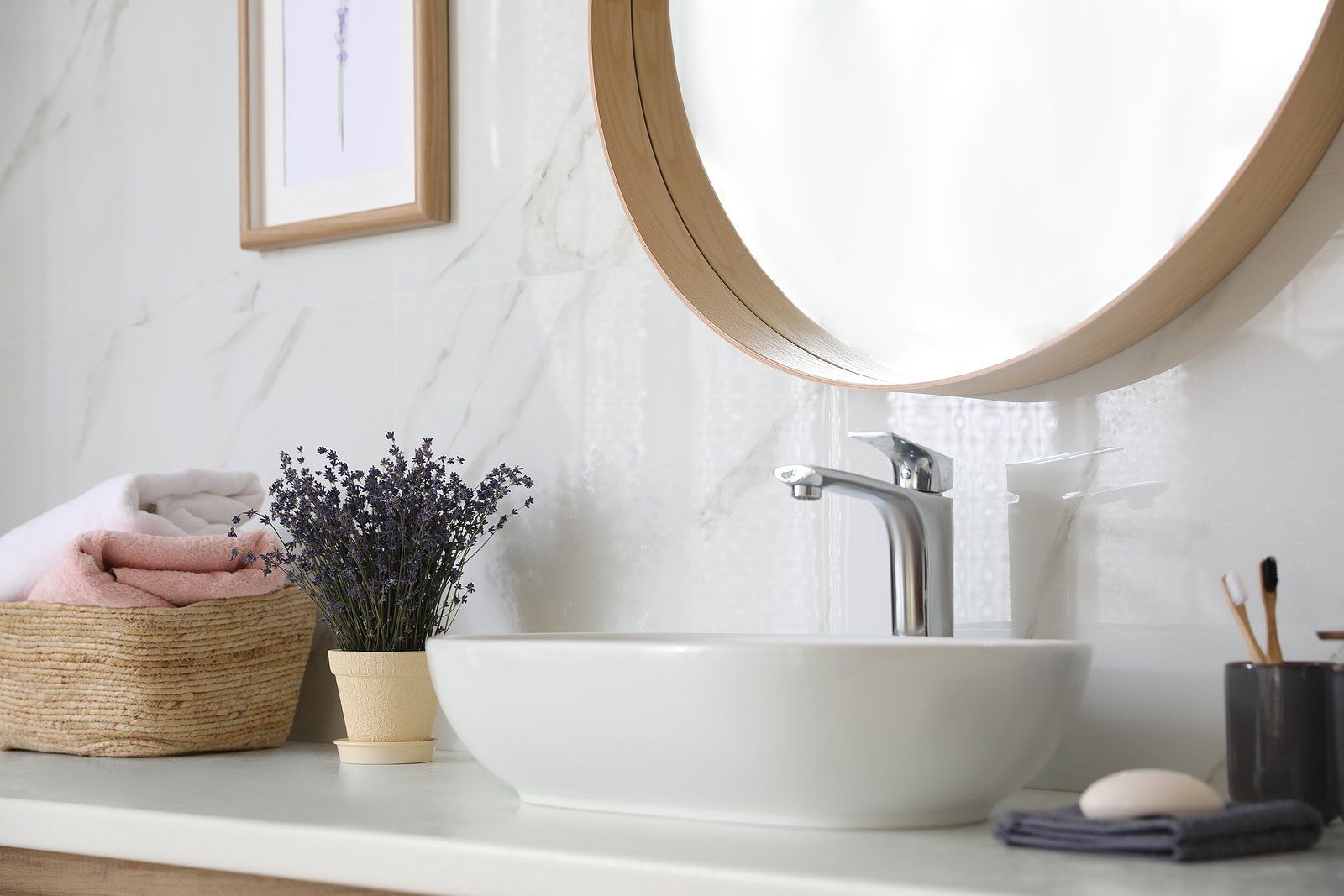 Bathroom Remodeling Services in Albany County, WY Minimalist bathroom vanity with white vessel sink, round mirror, and woven basket with towels and flowers