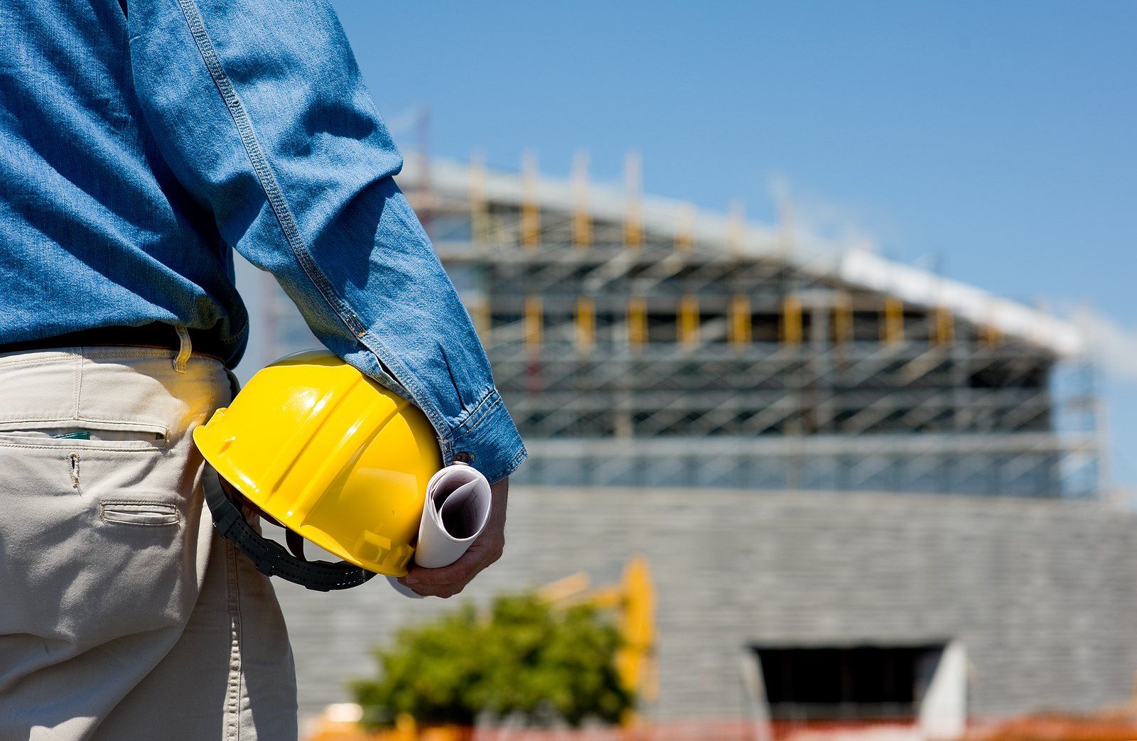 Bathroom Remodeling Services in Albany County, WY Construction worker holding a yellow hard hat in front of a building under construction