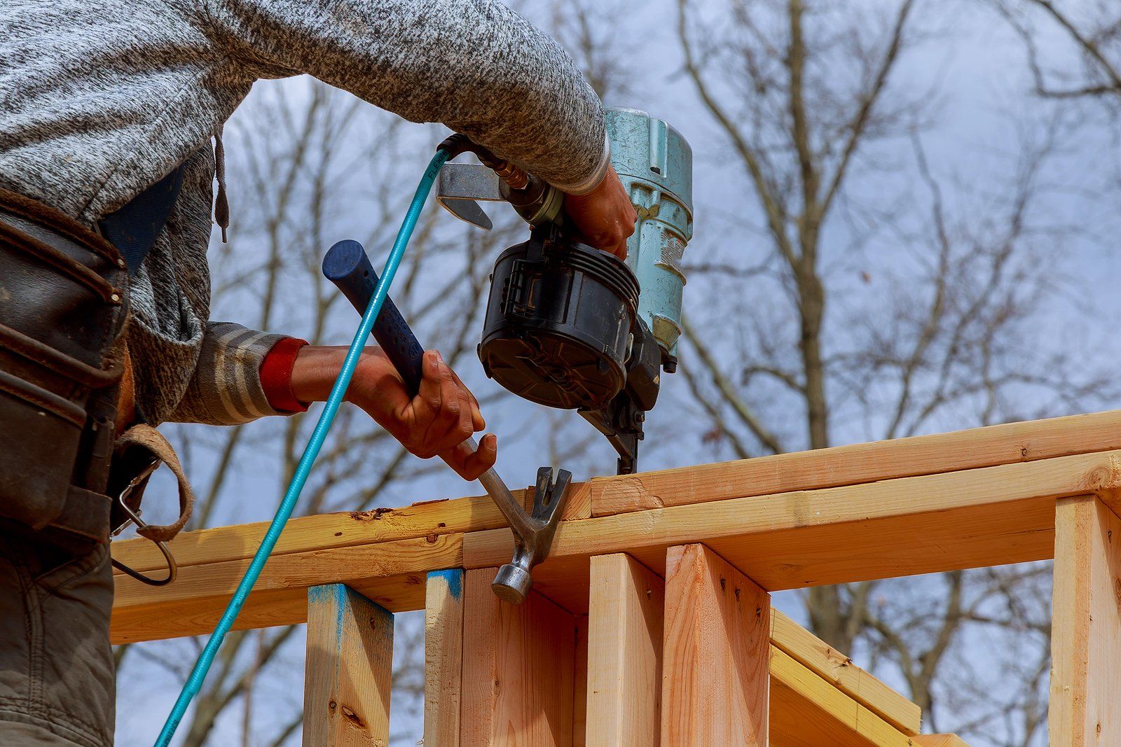 Bathroom Remodeling Services in Albany County, WY Worker using a drill to fasten wood framing at a construction site under a blue sky