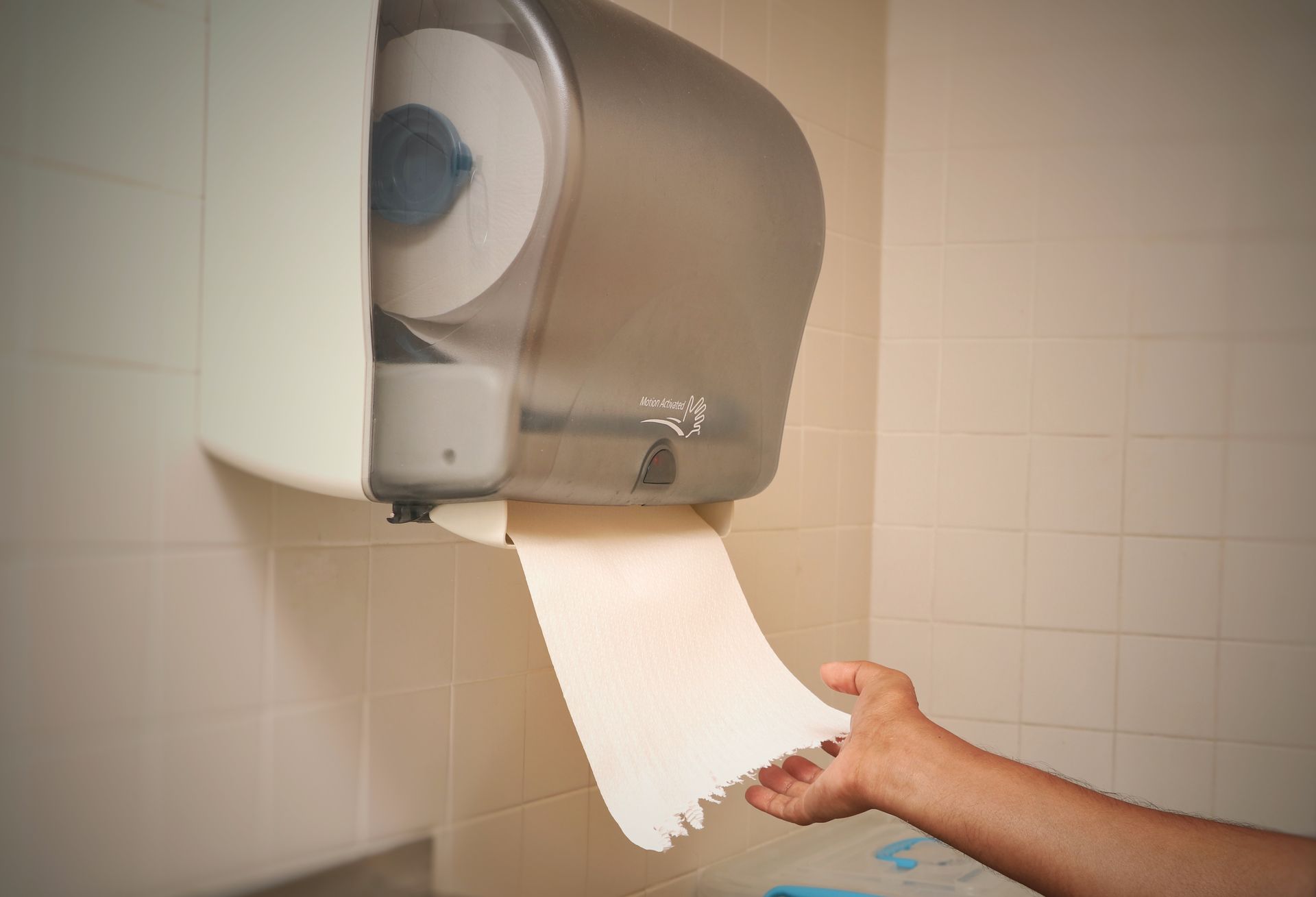 Bathroom Remodeling Services in Albany County, WY Hand reaching for a paper towel from a wall-mounted dispenser in a tiled restroom.