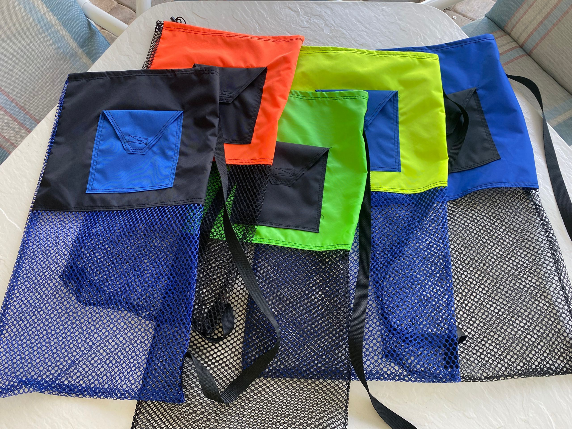 Stack of colorful mesh tote bags with blue, orange, green, and black panels