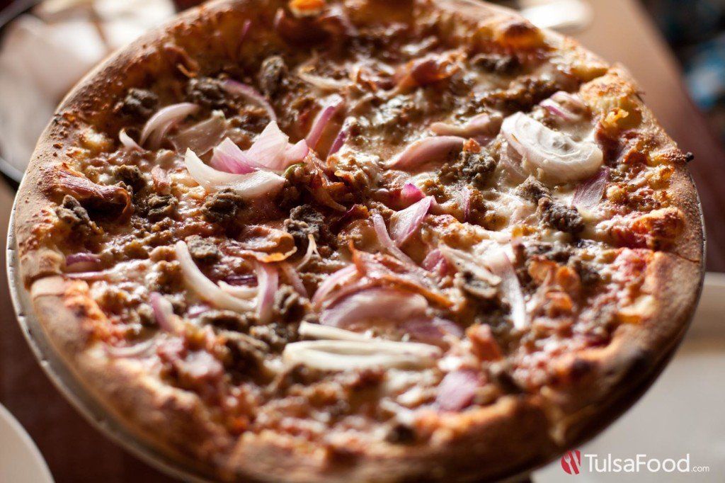 Pizza with red onions, mushrooms, and meat, on a metal tray.