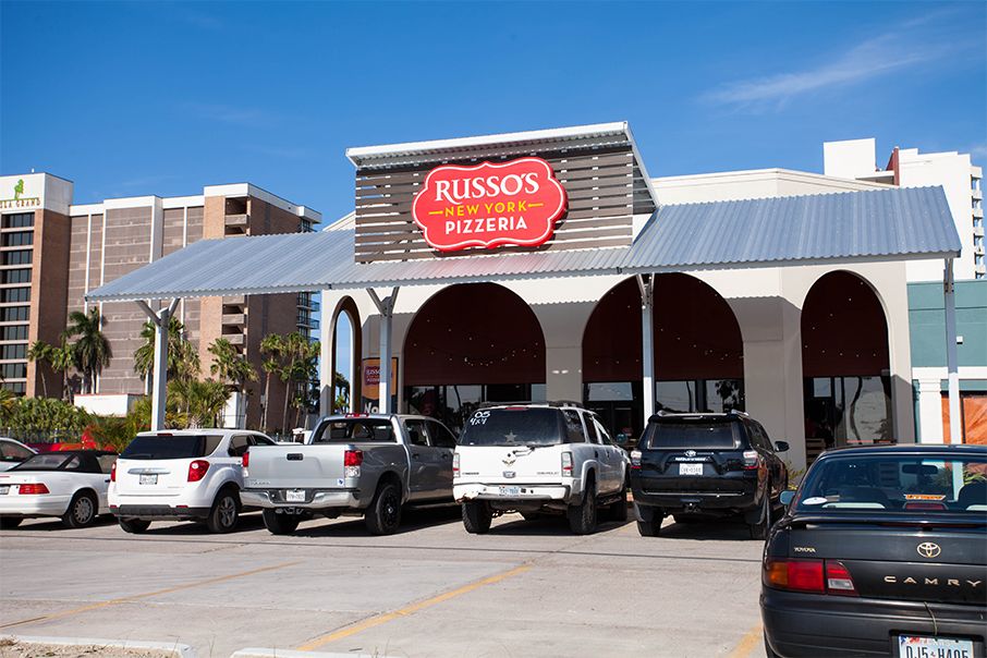 Russo's Coal Fired Italian Kitchen restaurant exterior with cars parked out front on a sunny day.
