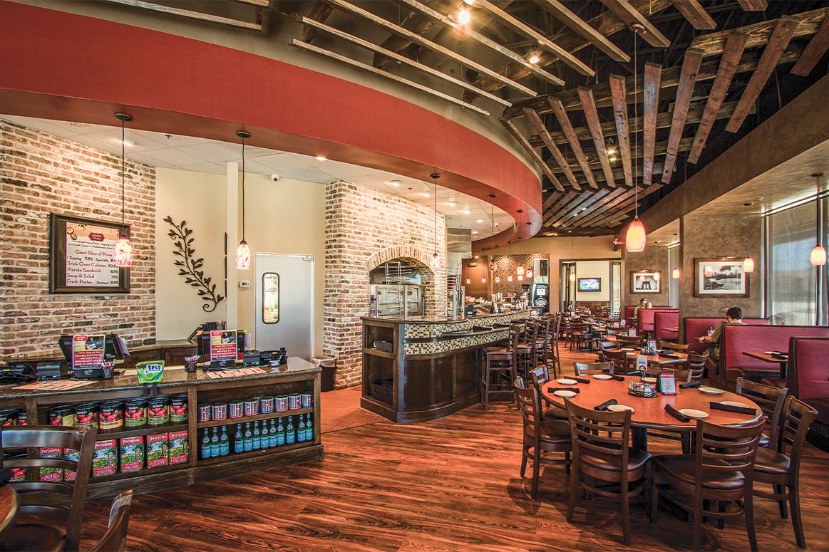 Interior of a restaurant with brick and wood accents, a bar, and dining tables.