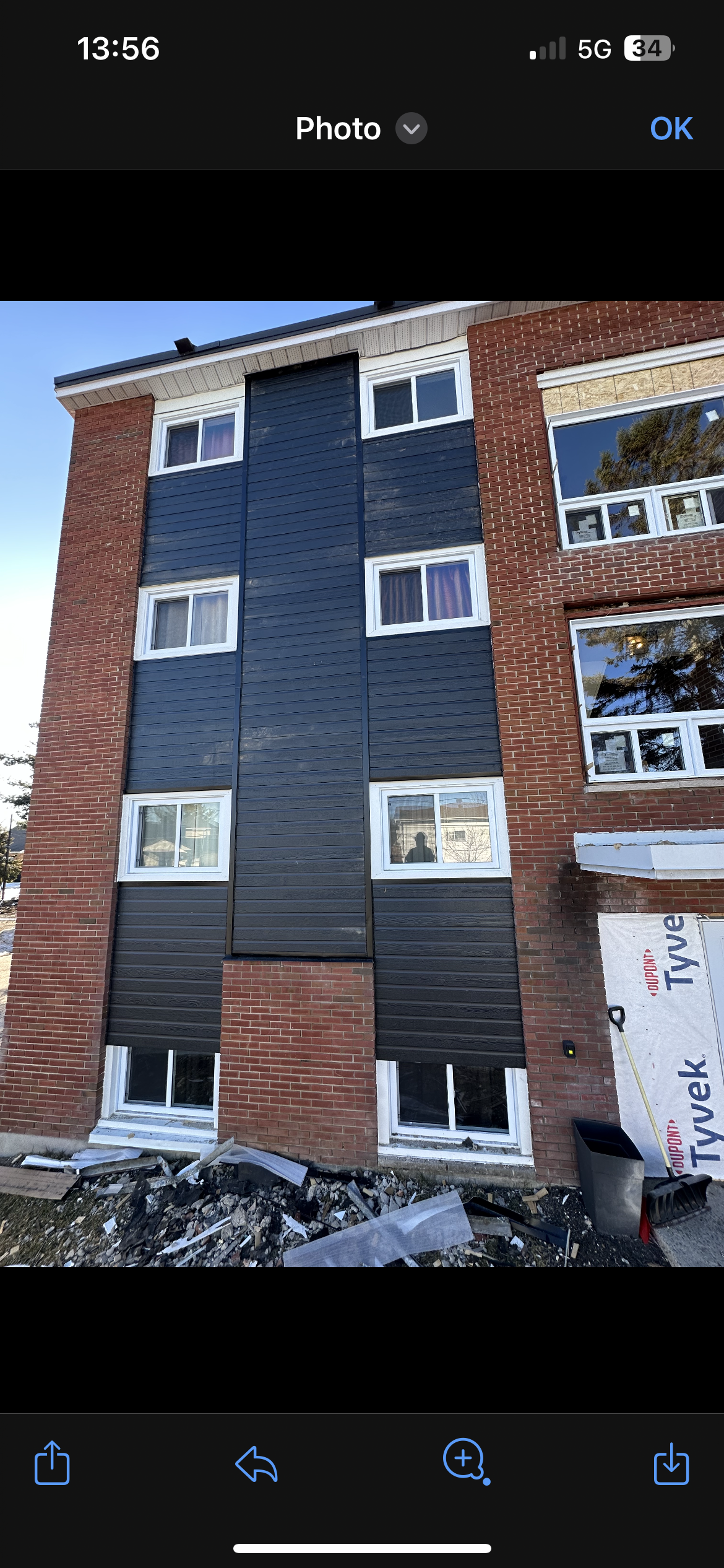 Immeuble d'appartements en briques blanches, avec un revêtement bleu foncé et des fenêtres à cadre blanc.