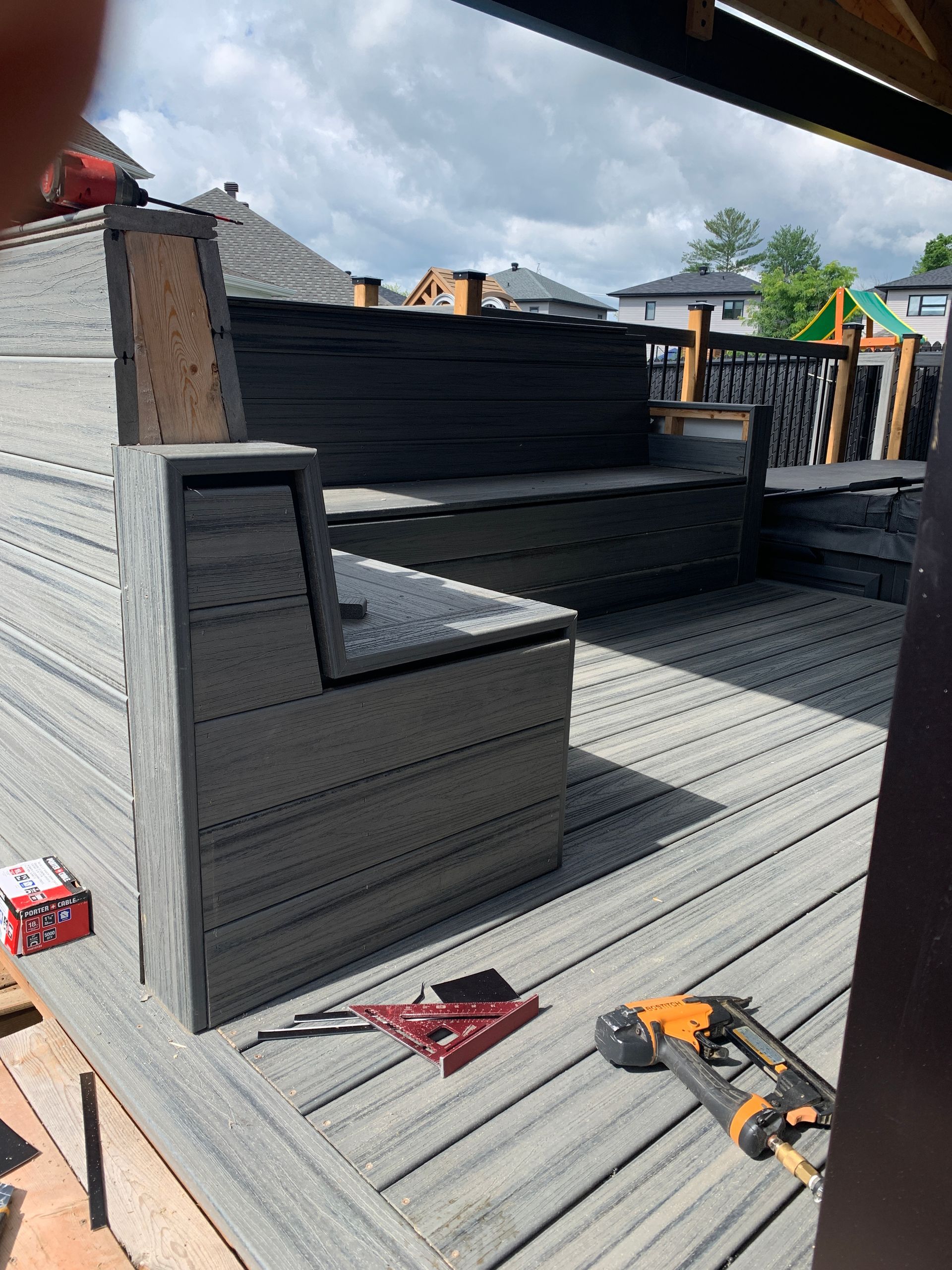 Terrasse arrière avec canapés d'extérieur noirs, sol gris et outils de construction