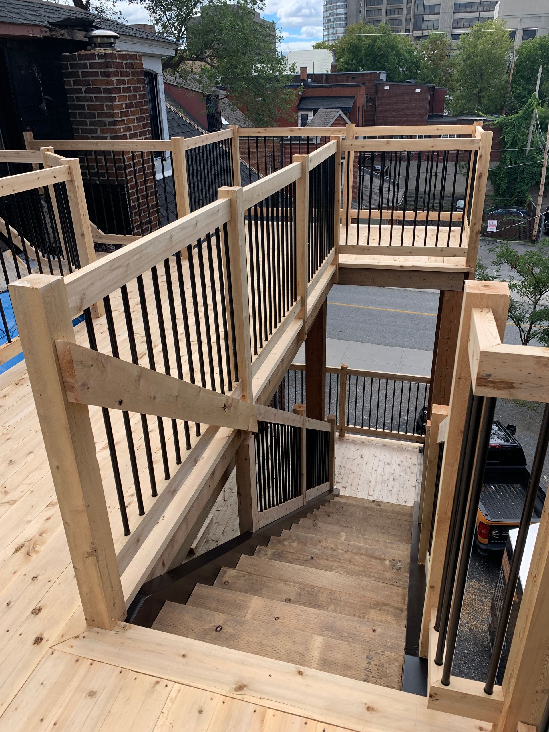 Escalier extérieur en bois avec rampes et paliers entre bâtiments en briques