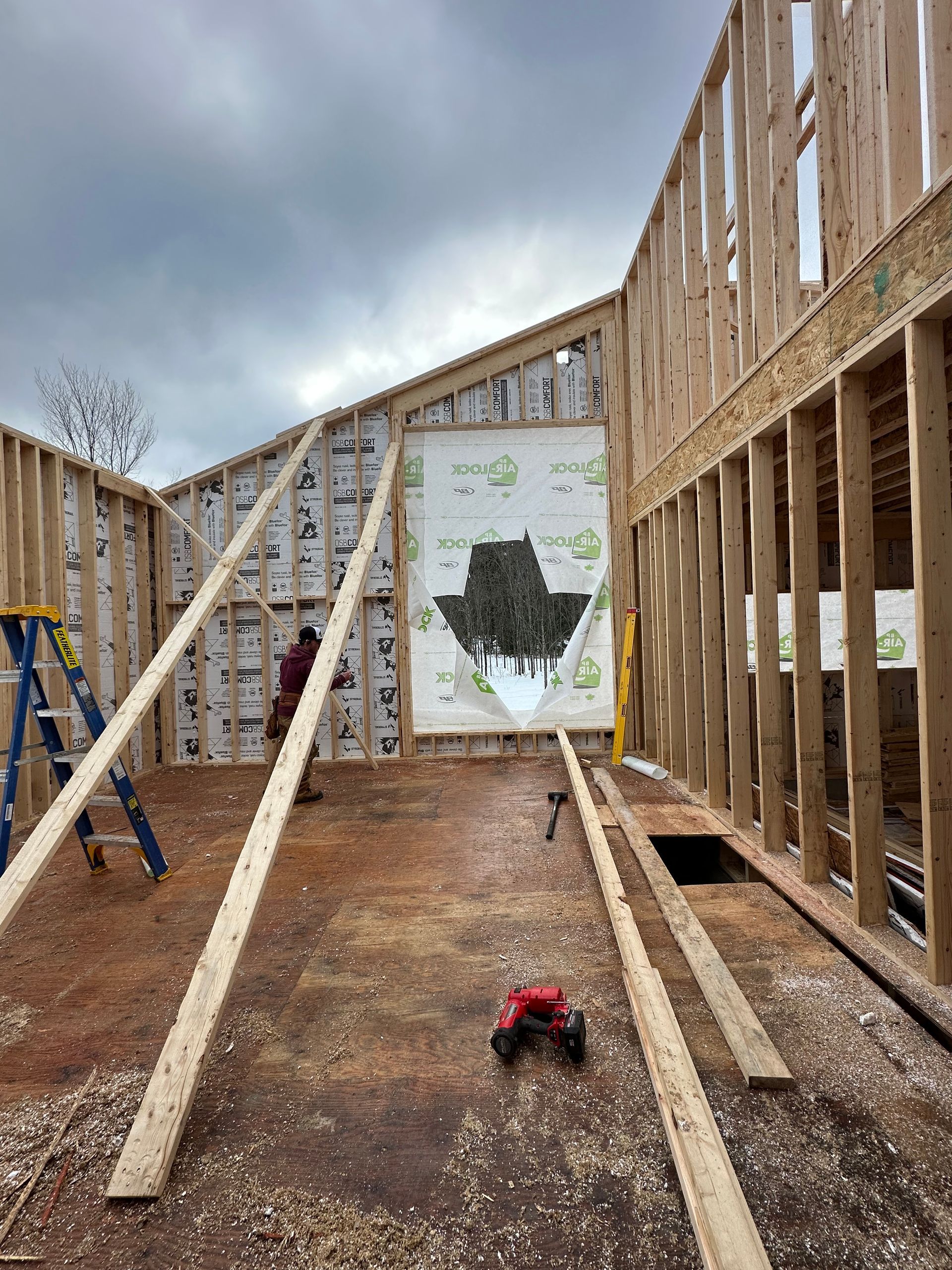 Intérieur d'un chantier de construction avec charpente en bois, étais, sol boueux et ciel nuageux au-dessus