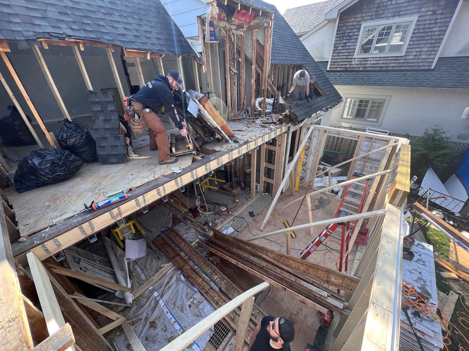 Des ouvriers du bâtiment construisent la charpente d'une terrasse à plusieurs niveaux sur le toit d'une maison en rénovation.