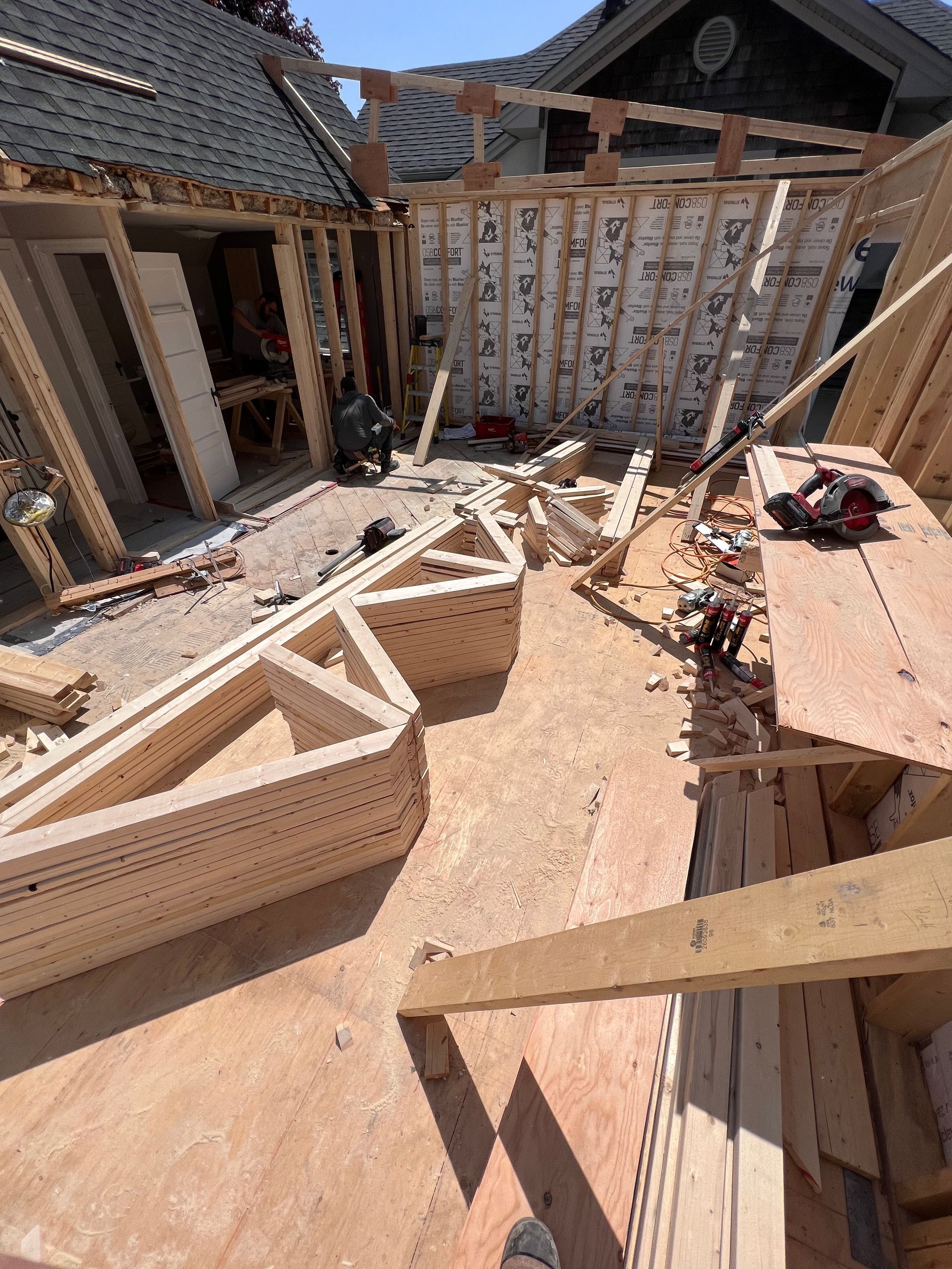 Structure en bois partiellement construite avec charpente apparente et toiture-terrasse sur un chantier de construction