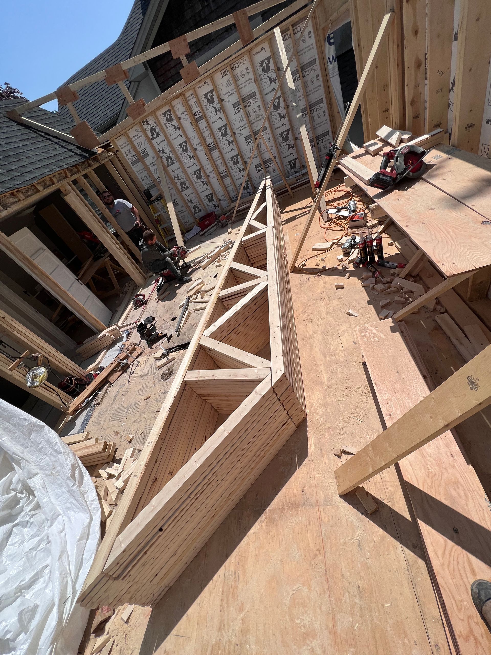 Chantier de construction avec charpentes en bois et débris dans une cour ensoleillée entre les bâtiments
