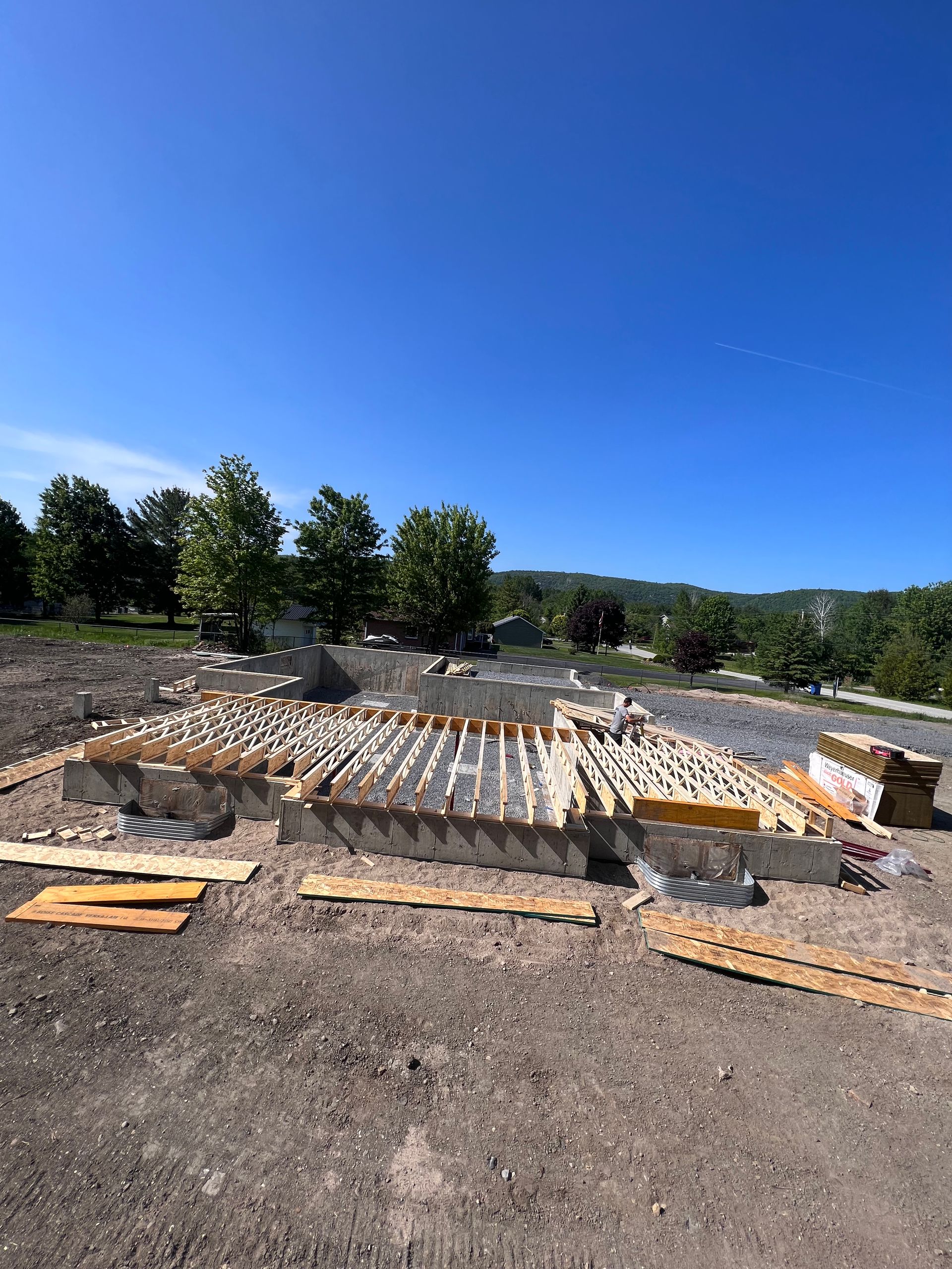 Chantier de fouilles avec coffrages en bois et fondations en béton sous un ciel bleu clair