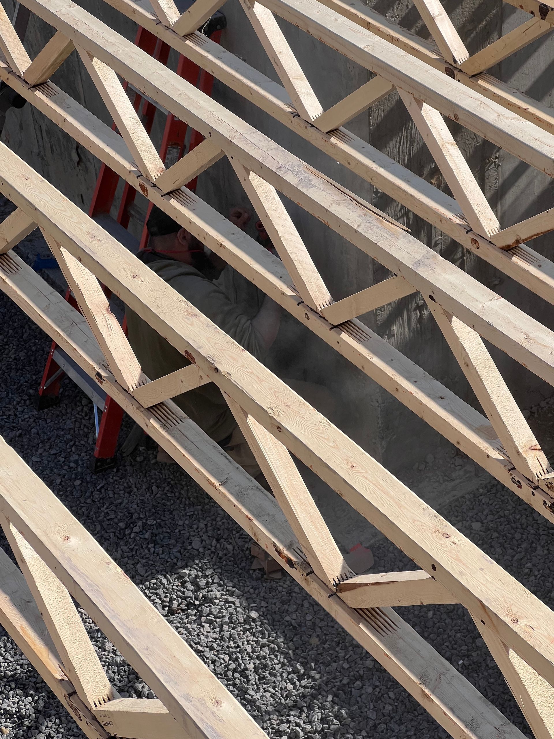 Des poutres en bois disposées en diagonale sur une surface d'asphalte grise forment un motif entrecroisé.